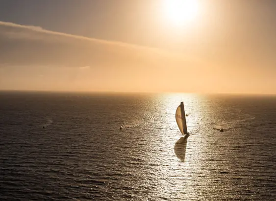 A yacht sailing across open ocean at golden hour during the Sydney to Hobart Yacht Race