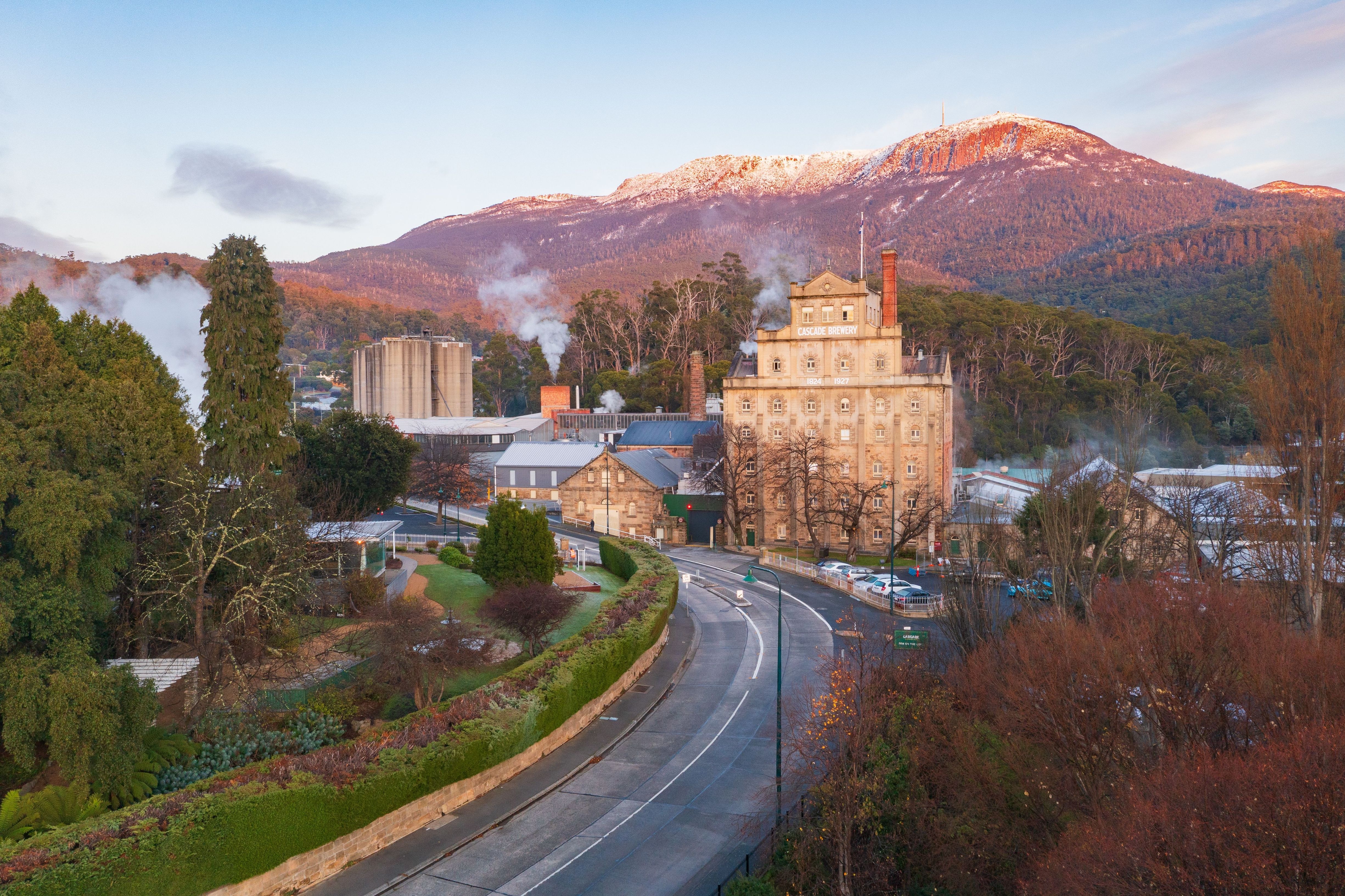 Cascade Brewery's heritage sandstone building beneath snow-dusted kunanyi / Mount Wellington, South Hobart