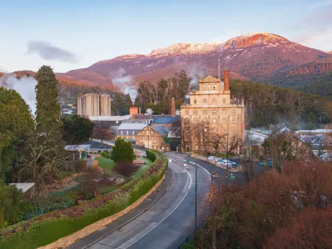 Cascade Brewery's heritage sandstone building beneath snow-dusted kunanyi / Mount Wellington, South Hobart