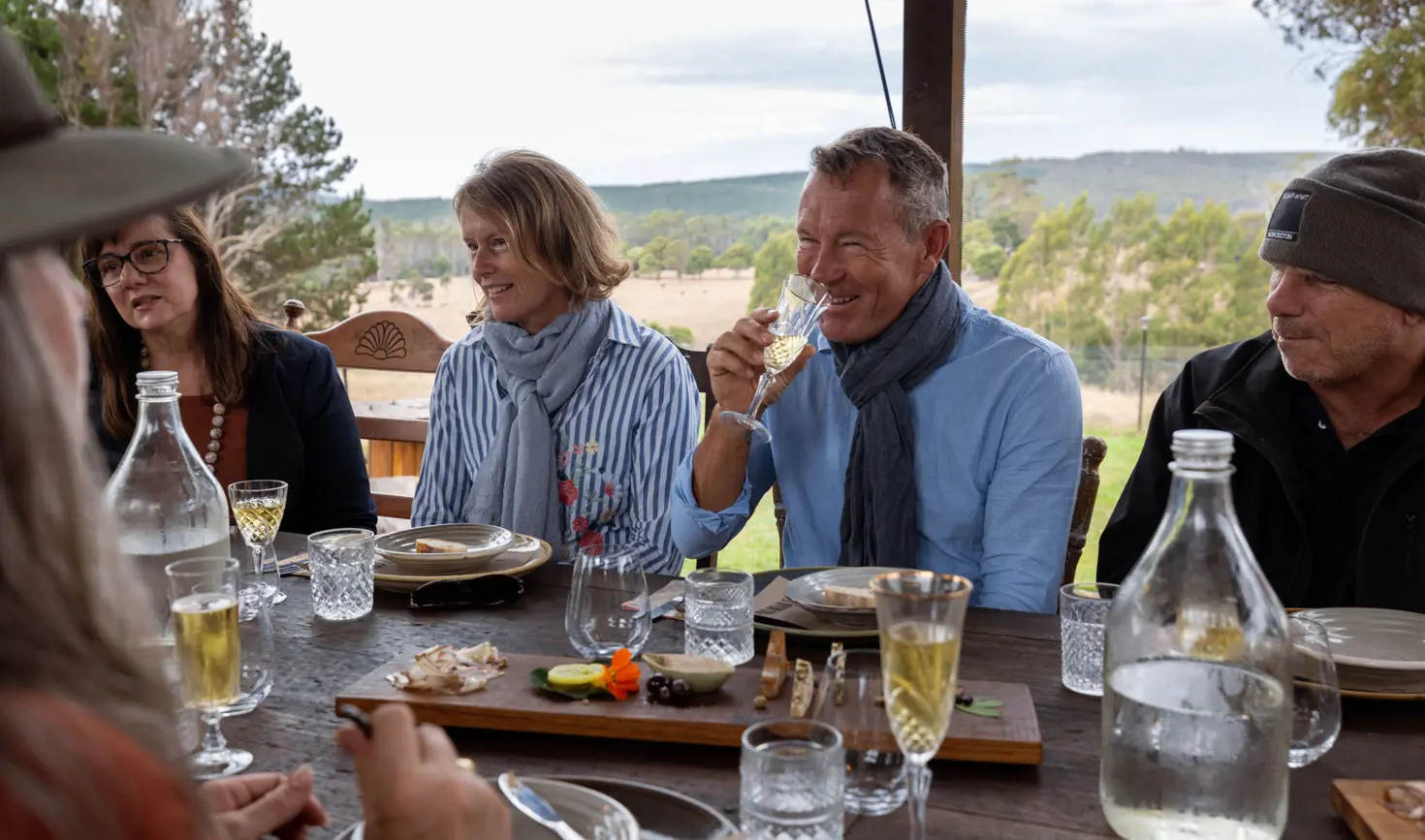 Guests enjoying a long table lunch with shared platters and wine overlooking rolling farmland at Fork it Farm, Lebrina