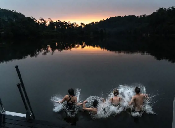 Four bathers leaping into the water from Floating Sauna Lake Derby at twilight, Derby