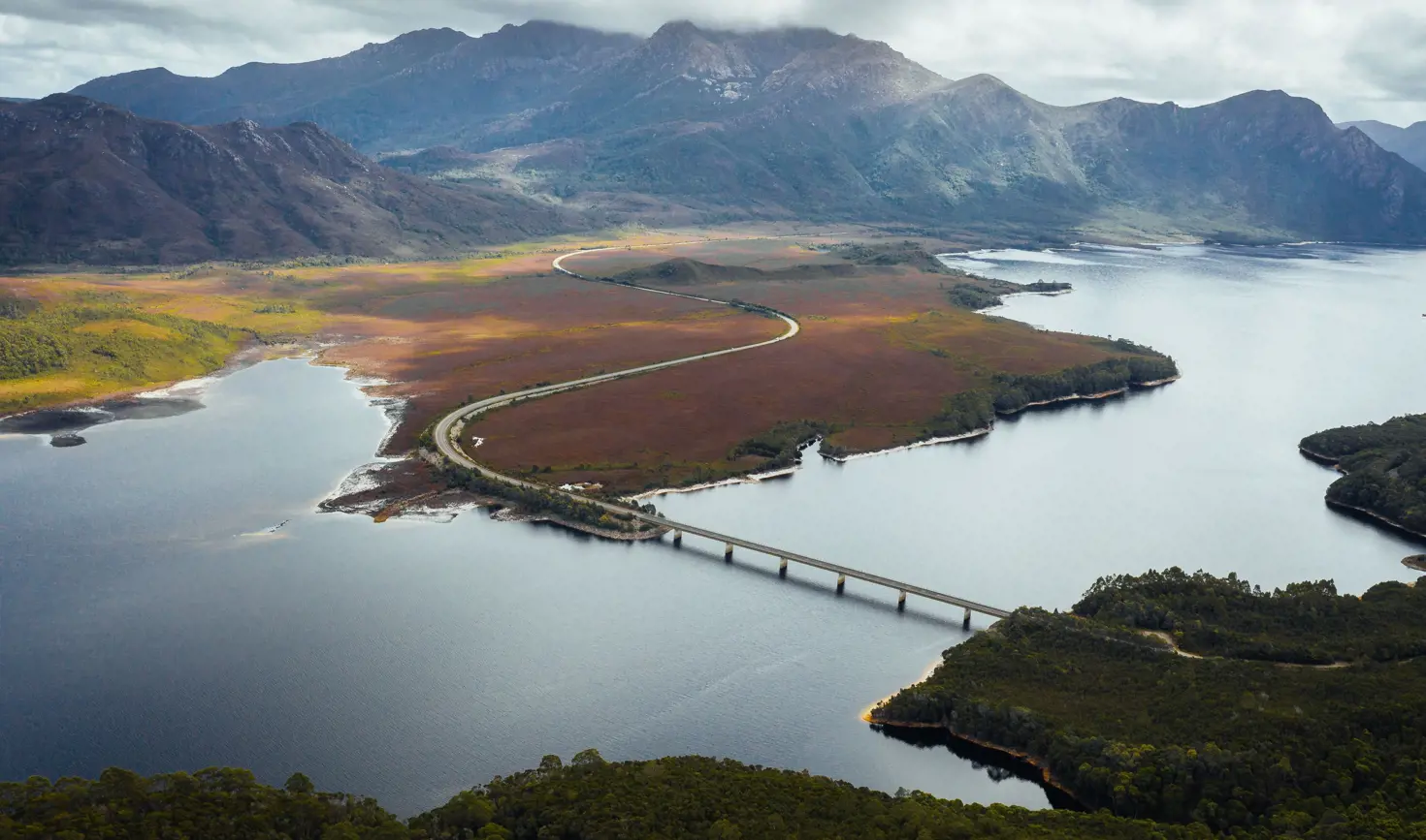 Aerial view of the Lyell Highway crossing the bridge over Lake Burbury with mountain ranges beyond, west coast