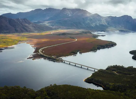 Aerial view of the Lyell Highway crossing the bridge over Lake Burbury with mountain ranges beyond, west coast