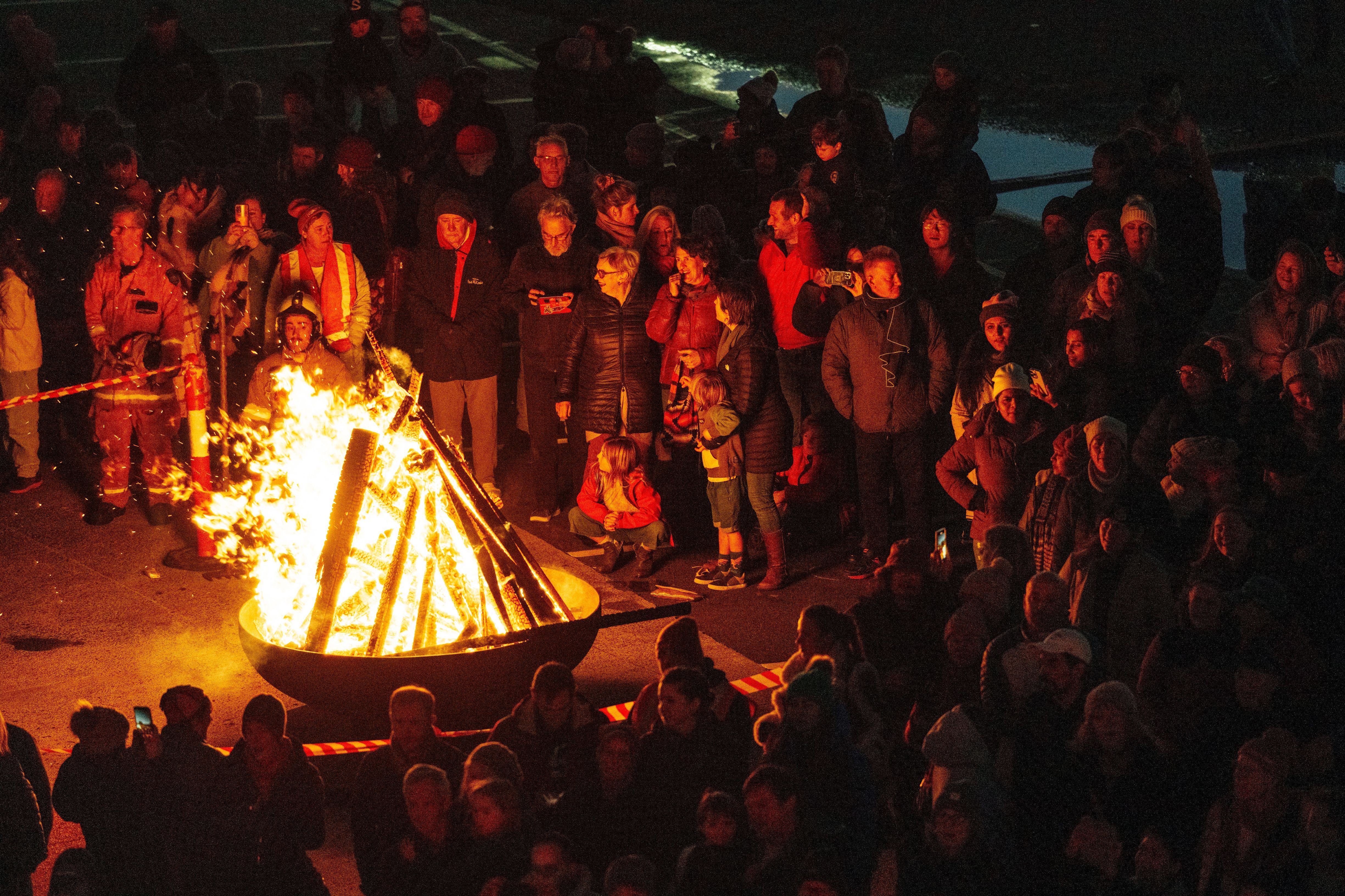 A crowd gathered around a blazing fire pit with fire safety personnel at the Big Sing Bonfire, Festival of Voices, Hobart