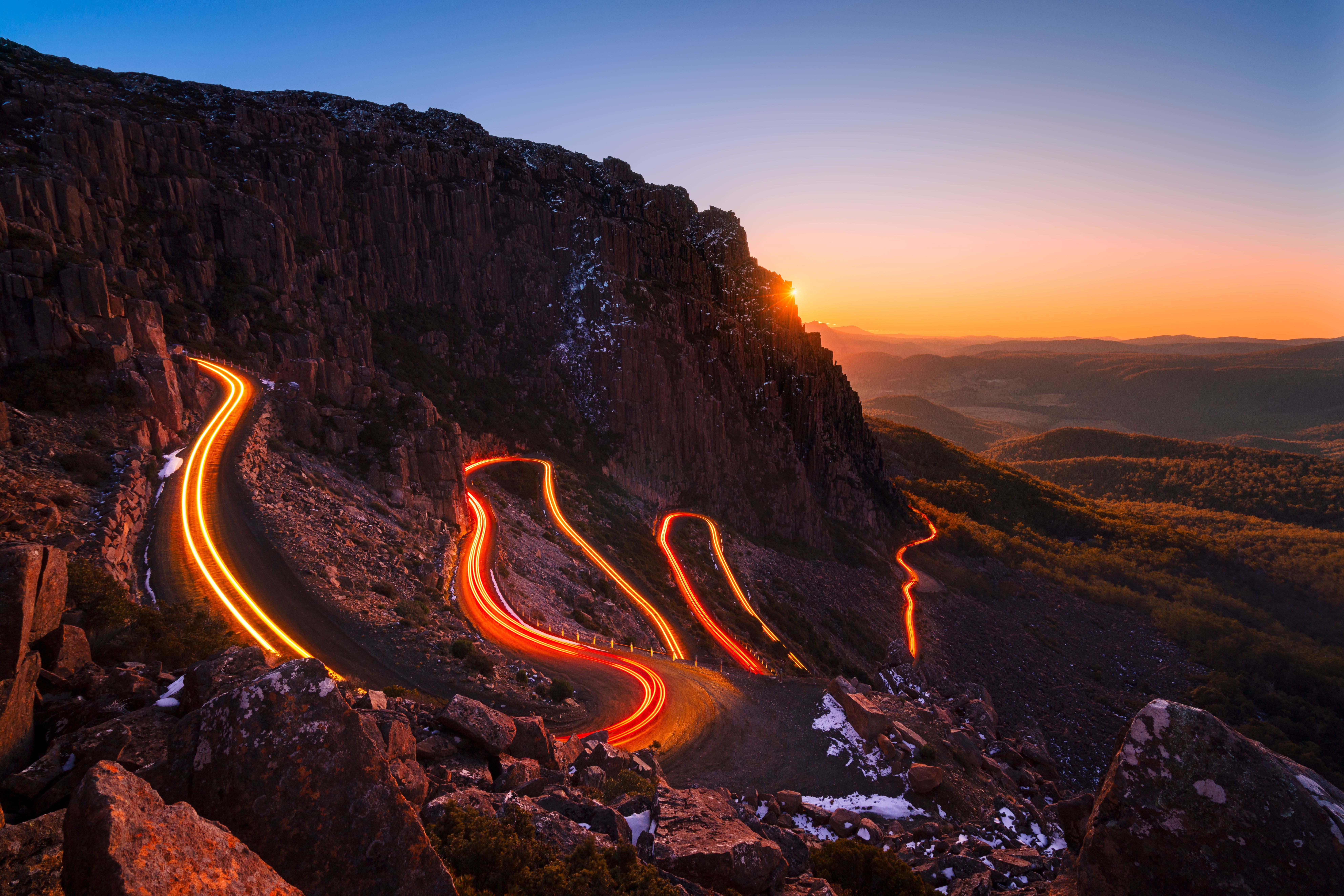 Vehicle light trails curving along the Jacob's Ladder hairpin road at twilight, Ben Lomond National Park