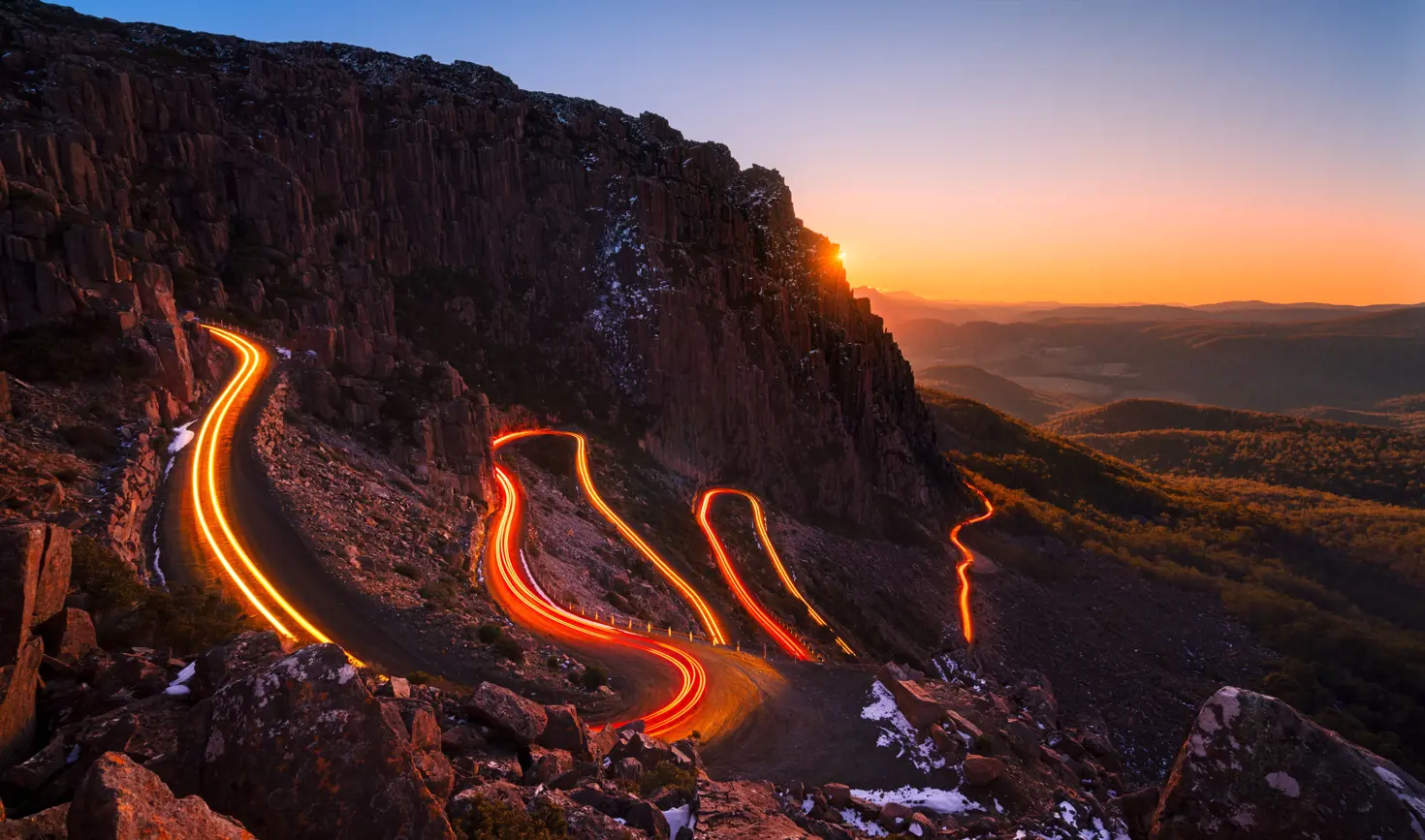 Vehicle light trails curving along the Jacob's Ladder hairpin road at twilight, Ben Lomond National Park