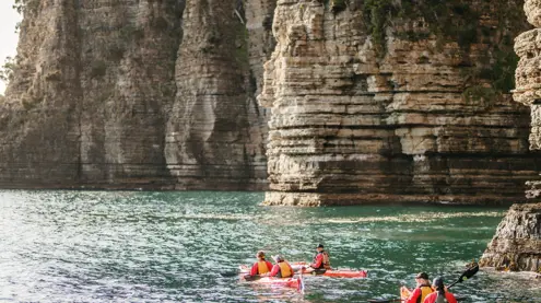 Sea kayakers paddle along dramatic coastal cliffs in Tasman National Park with Southern Sea Ventures