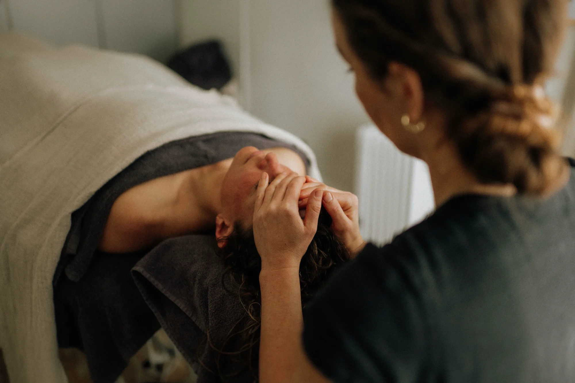 A therapist performs a facial massage on a client lying on a treatment table at Selkie Wellness in Bicheno
