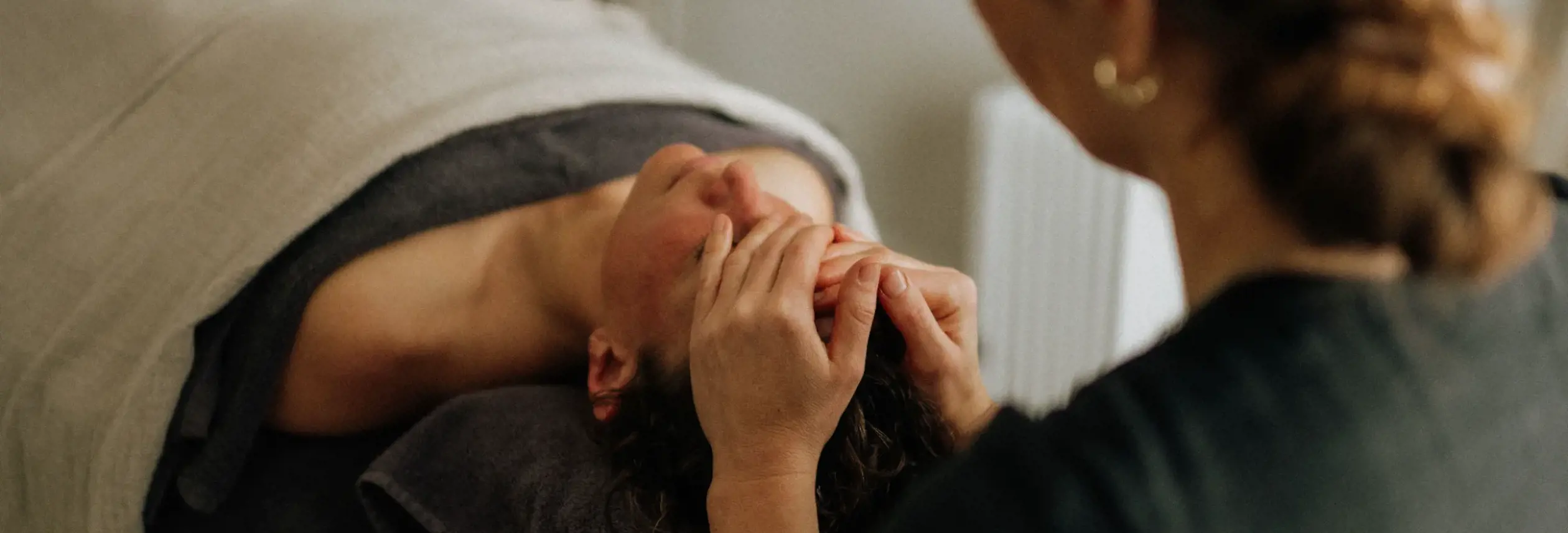 A therapist performs a facial massage on a client lying on a treatment table at Selkie Wellness in Bicheno