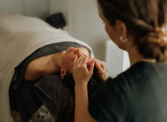 A therapist performs a facial massage on a client lying on a treatment table at Selkie Wellness in Bicheno
