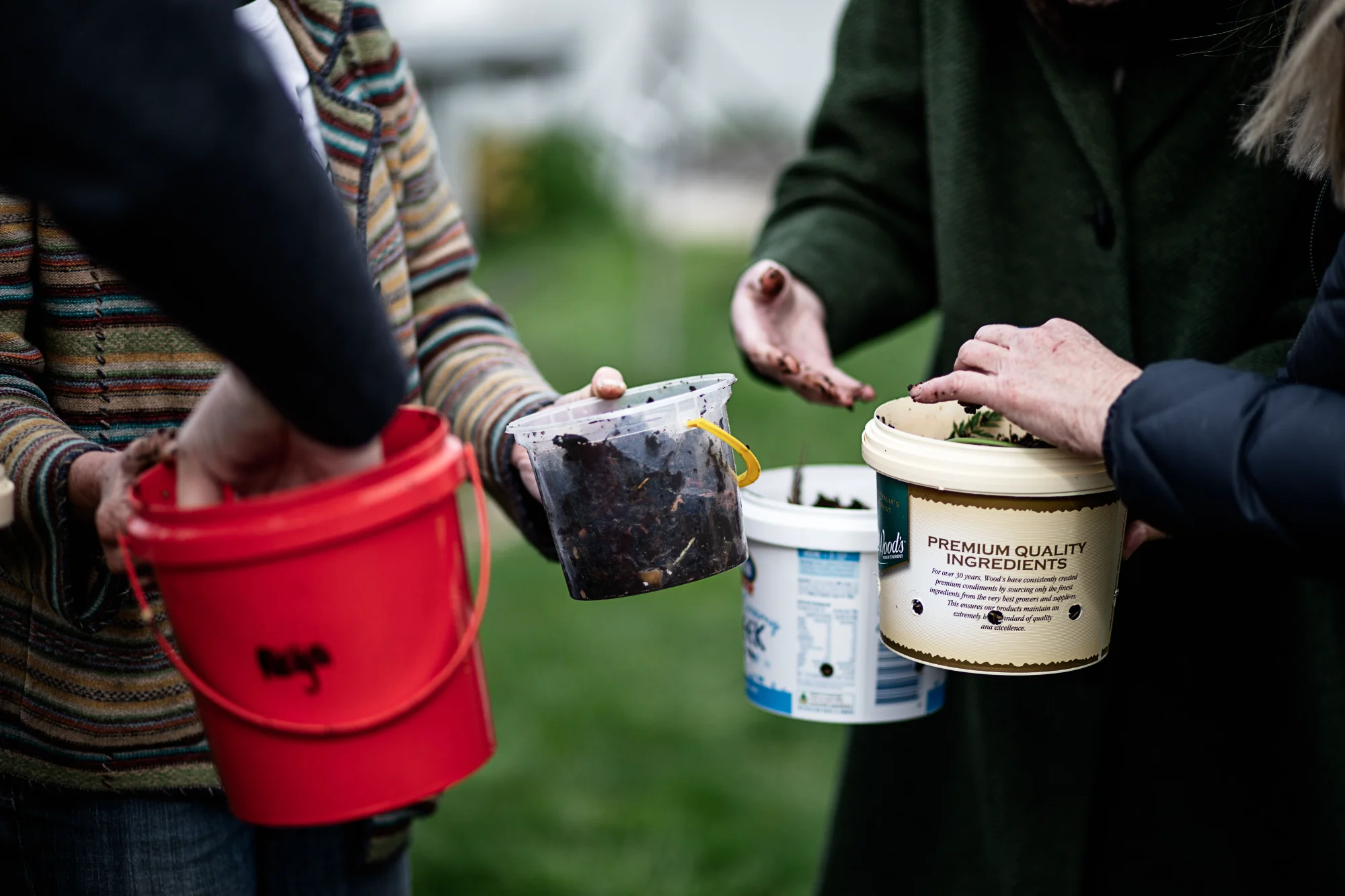 Close-up of people holding buckets of compost and soil at the AgriCULTURED Northern Suburbs Community Garden in Launceston