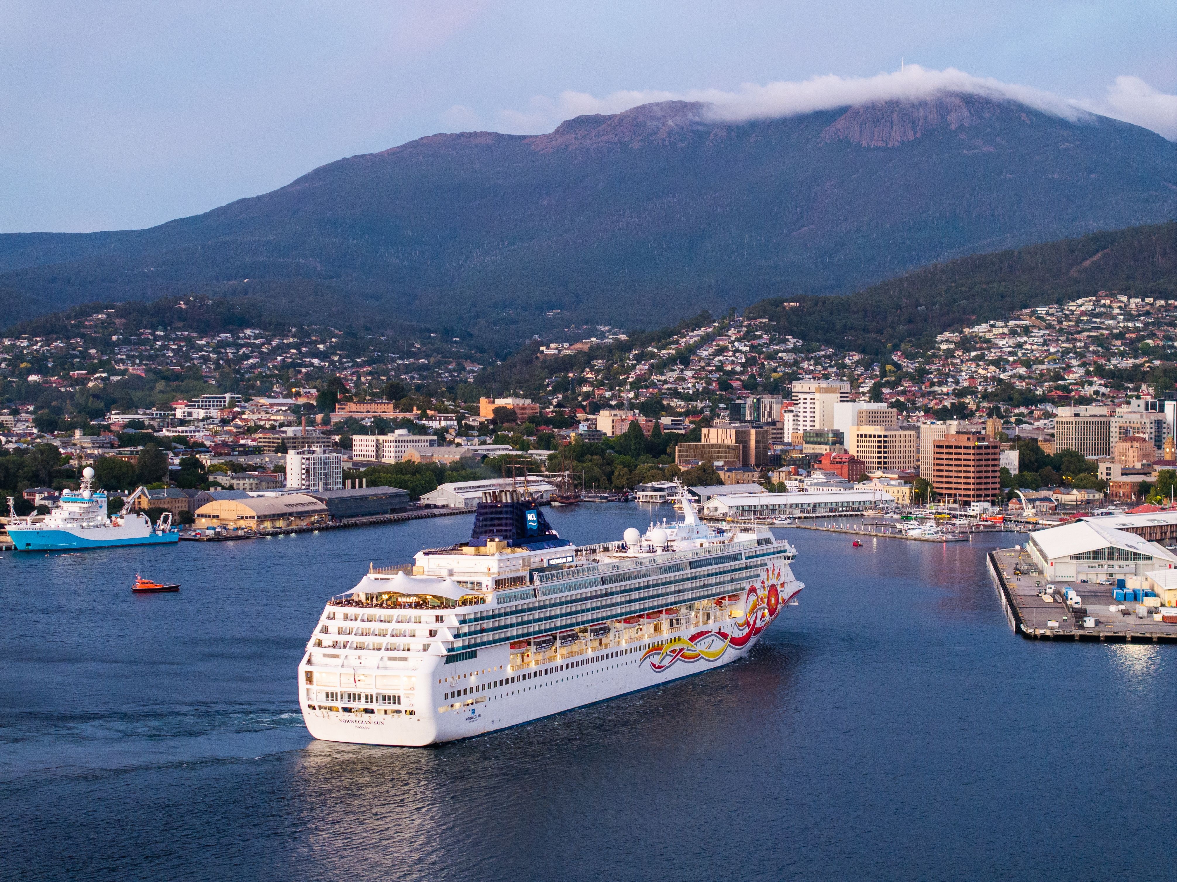 Norwegian Sun cruise ship sailing into Hobart Port with kunanyi / Mount Wellington and the city beyond