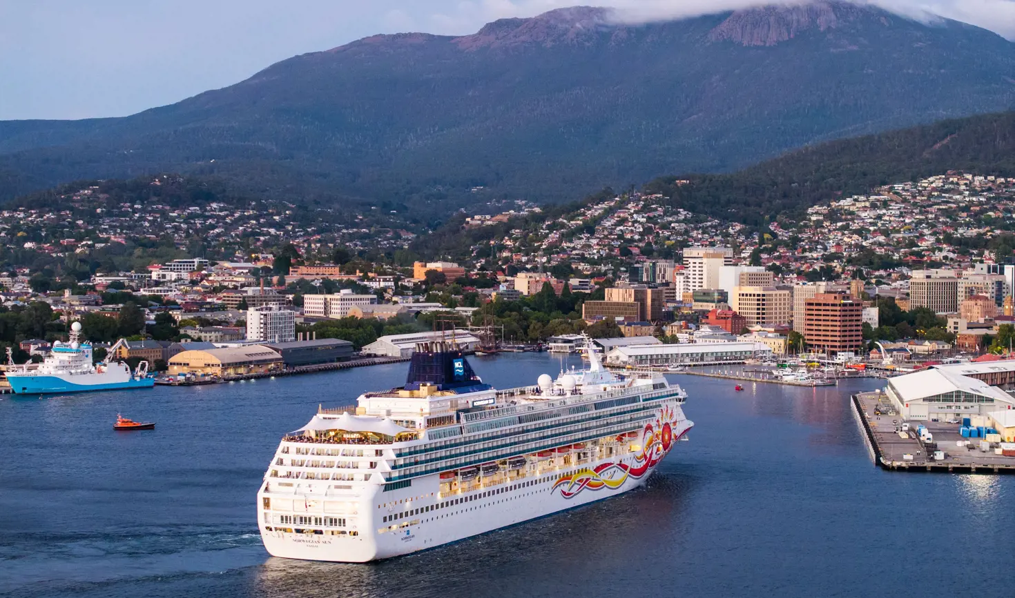Norwegian Sun cruise ship sailing into Hobart Port with kunanyi / Mount Wellington and the city beyond
