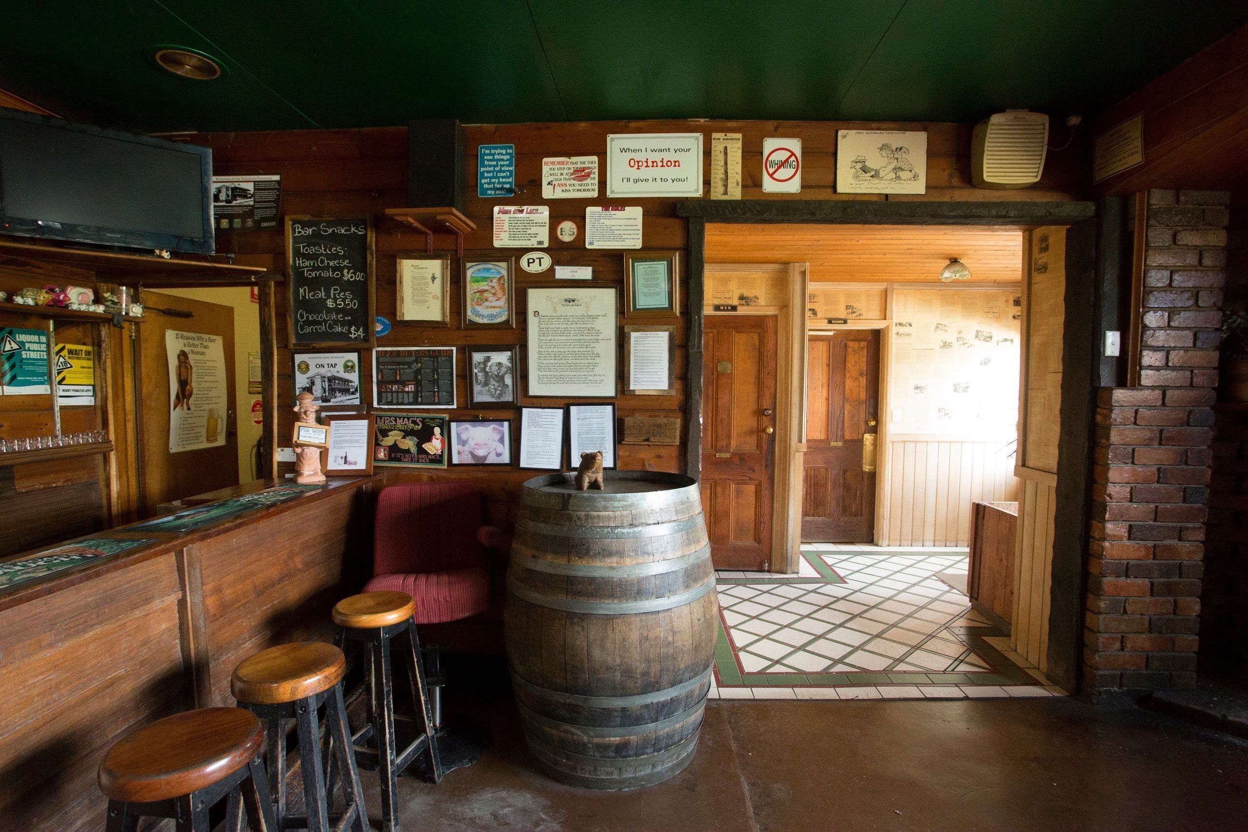 Interior of the Pub in the Paddock in Pyengana with timber bar stools, a wooden barrel and memorabilia-covered walls