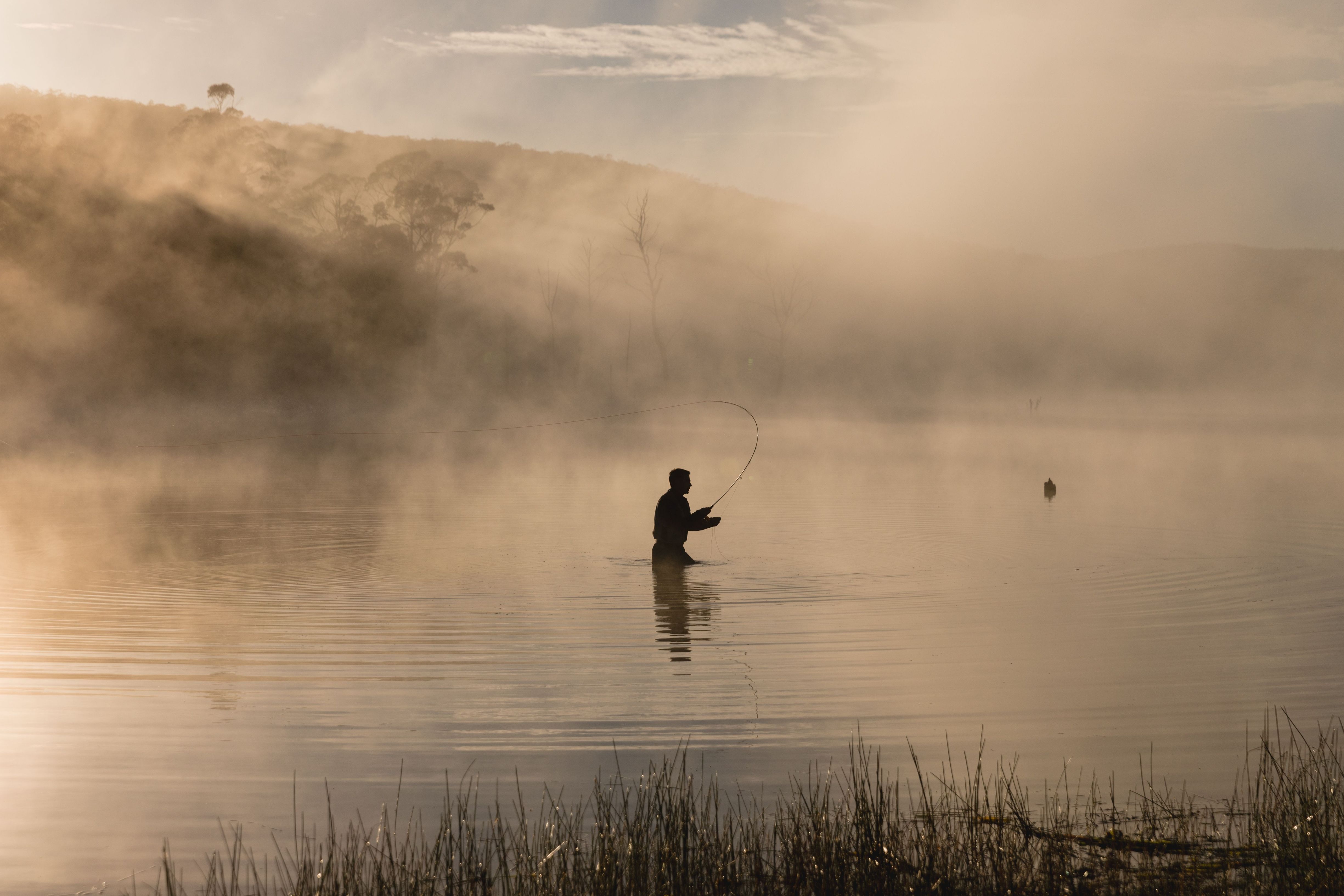 Silhouette of a fly fisher casting on misty Lake Leake, Tasmania's east coast