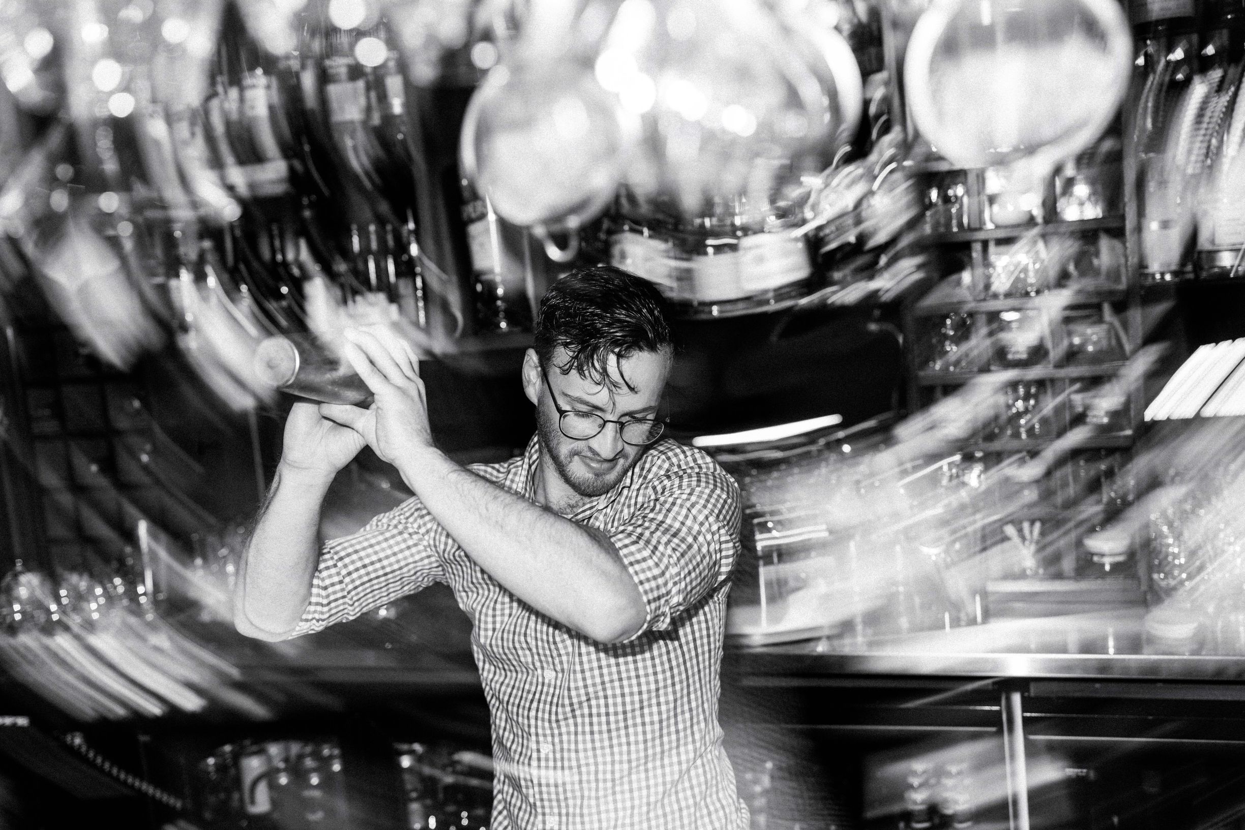 Black and white image of a bartender shaking a cocktail at Oscura by Bar Stelo, Launceston, Tasmania