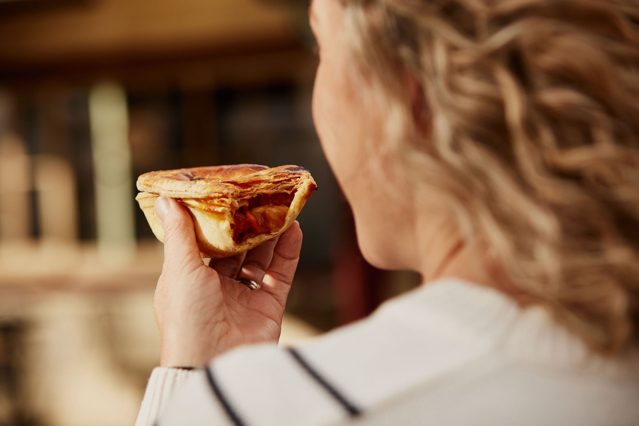 Close-up of a person holding a Tasmanian scallop pie with a bite taken out