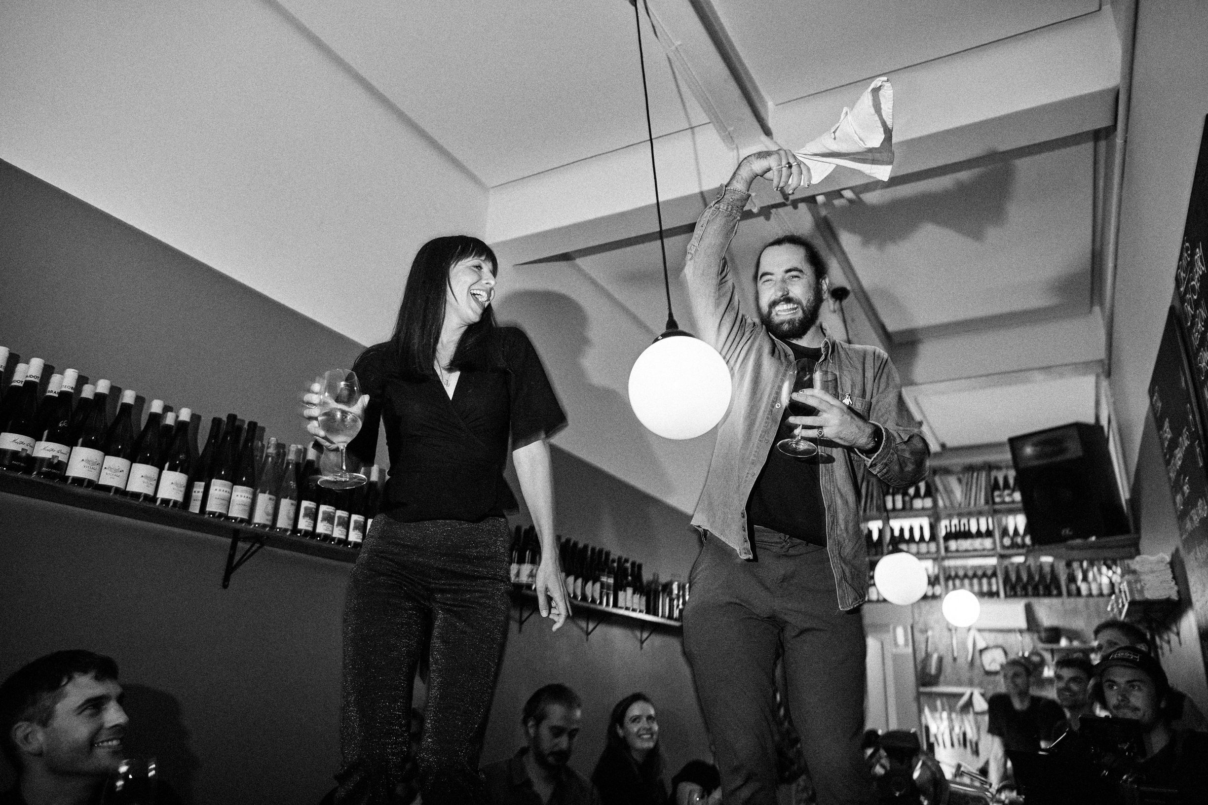 Black and white image of two people celebrating with wine glasses at Sonny wine bar, Hobart