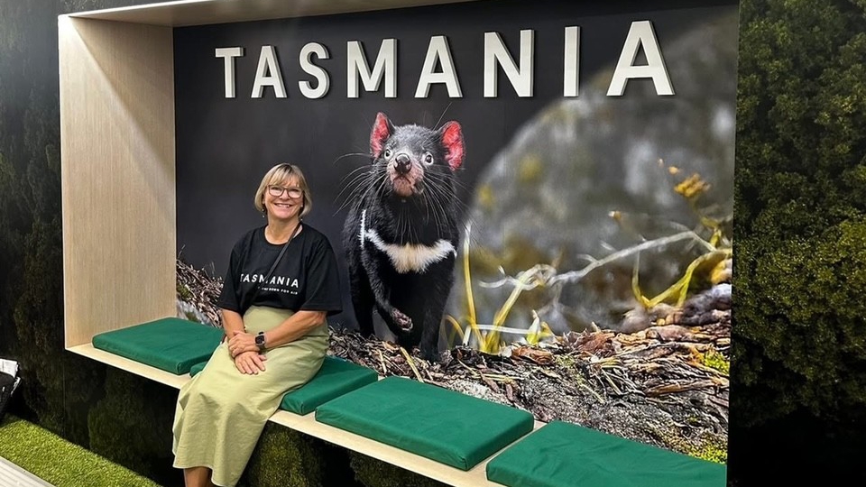 Karen Stotz seated beside a large Tasmanian devil photograph