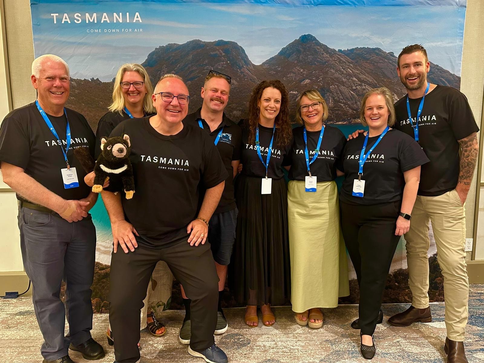 Karen Stotz with a group in Tasmania t-shirts in front of a Come Down For Air backdrop