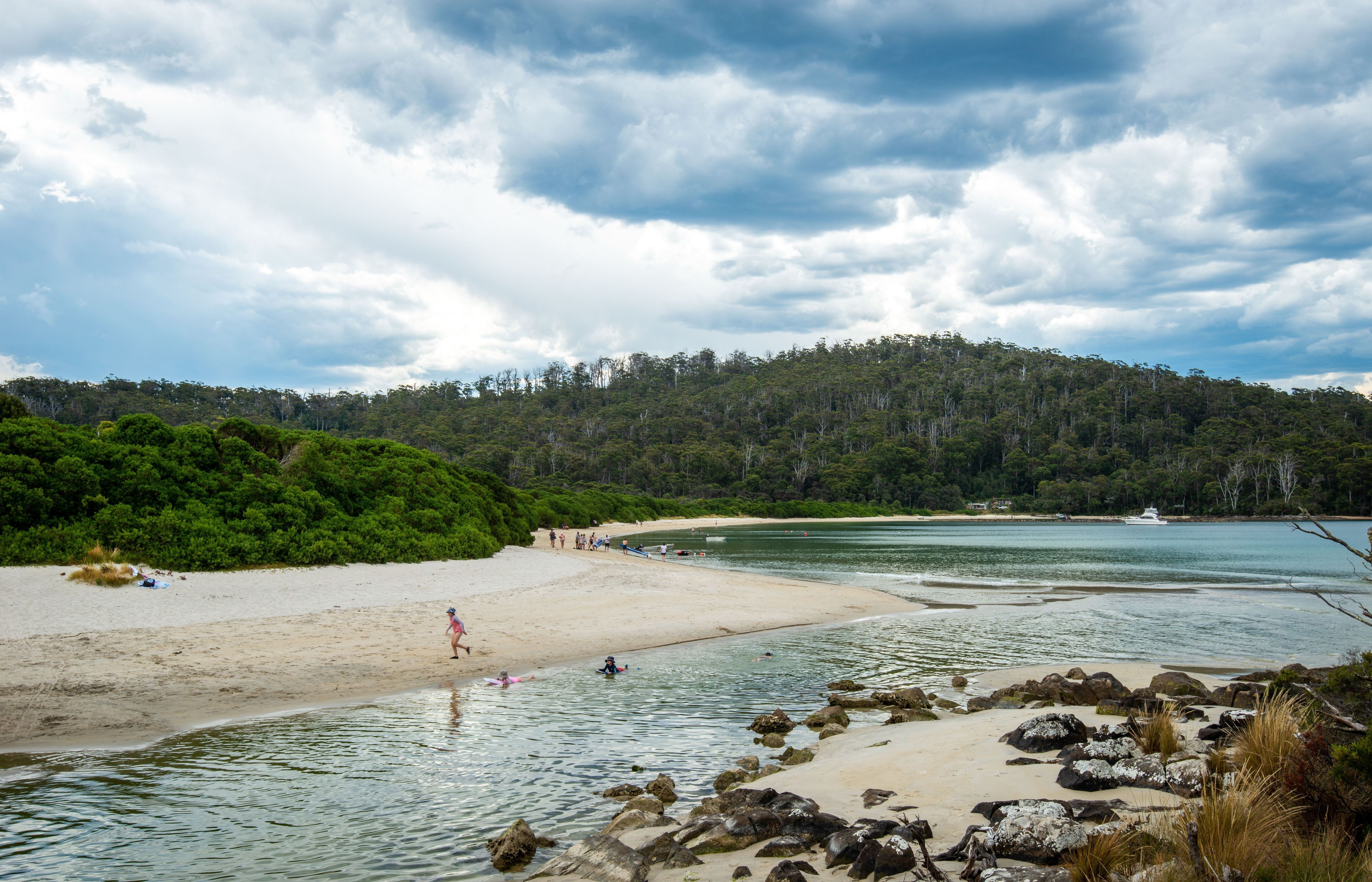 People swimming and playing on the sandy beach at Cockle Creek, Southwest National Park, Tasmania