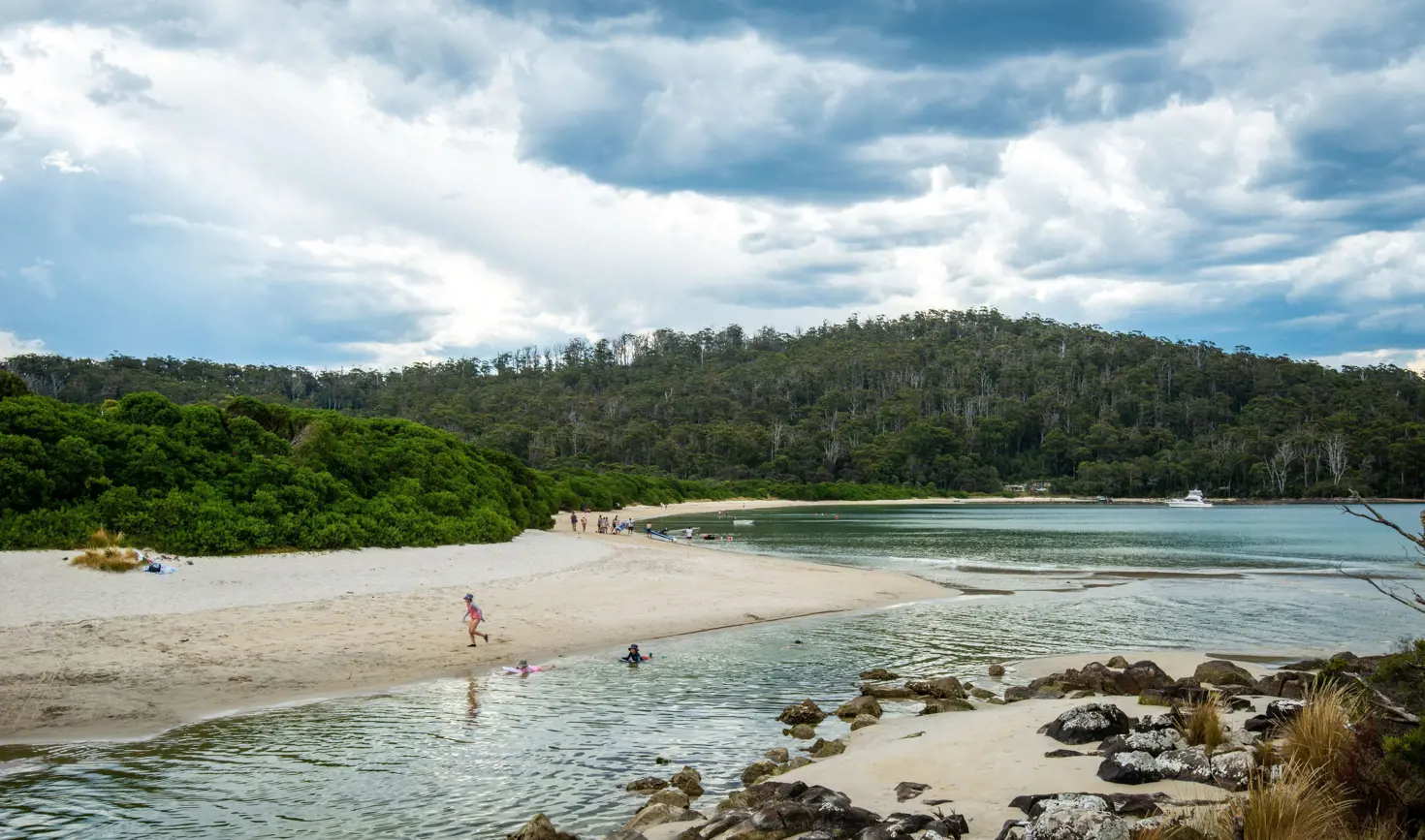 People swimming and playing on the sandy beach at Cockle Creek, Southwest National Park, Tasmania