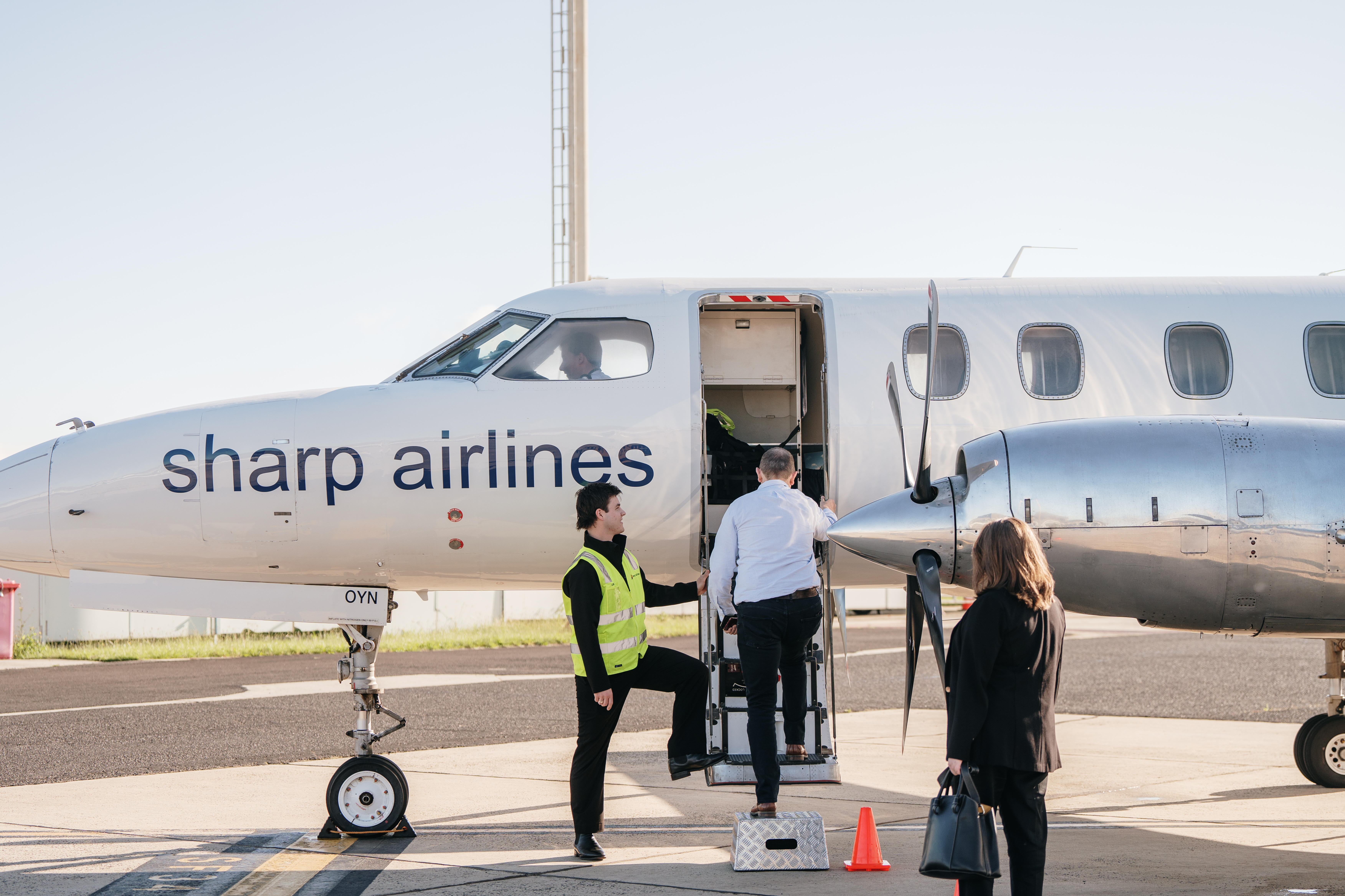 Passengers boarding a Sharp Airlines propeller plane with ground crew assisting on the tarmac, King Island