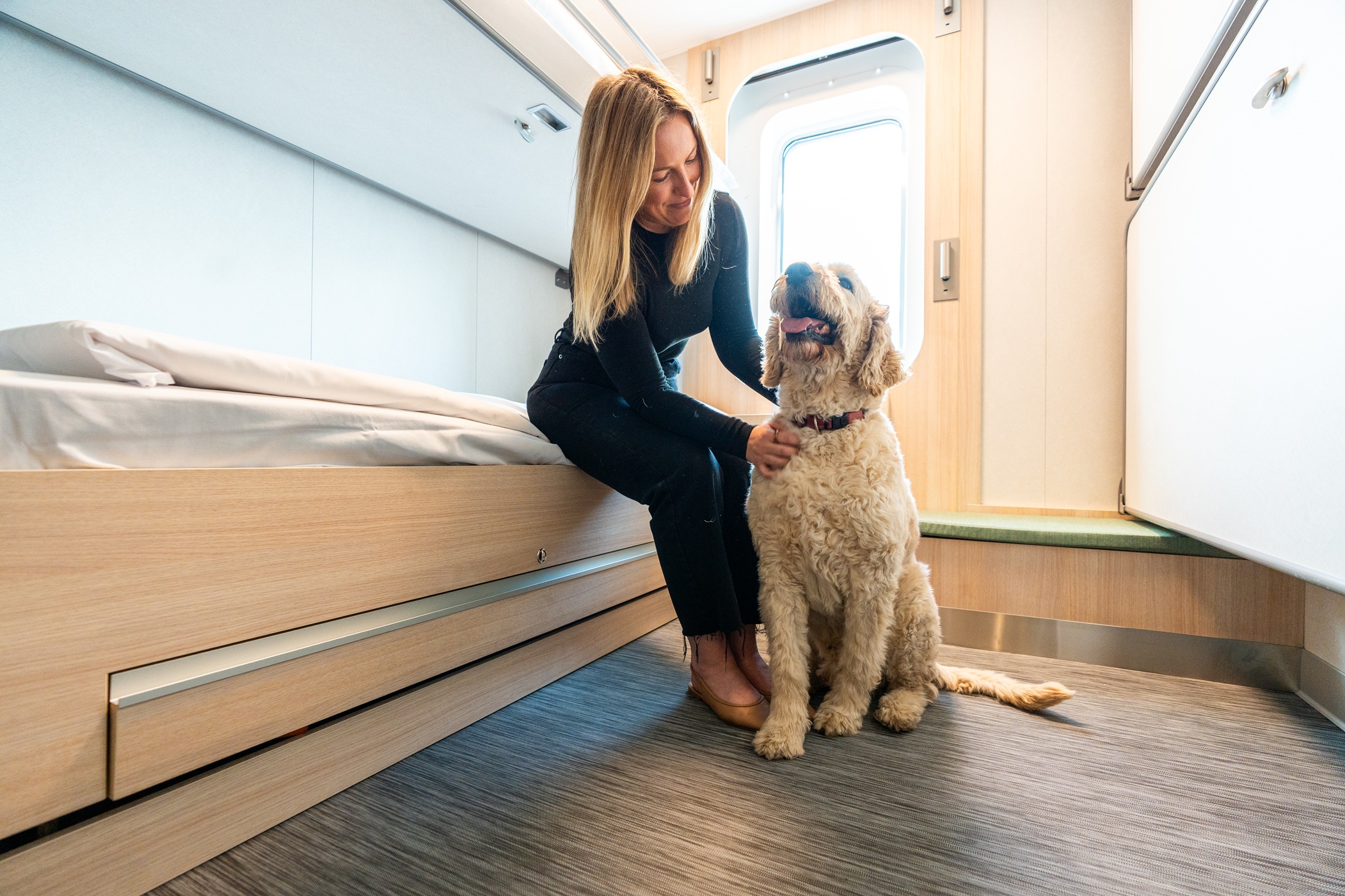 Woman patting a dog in a Spirit of Tasmania pet-friendly cabin