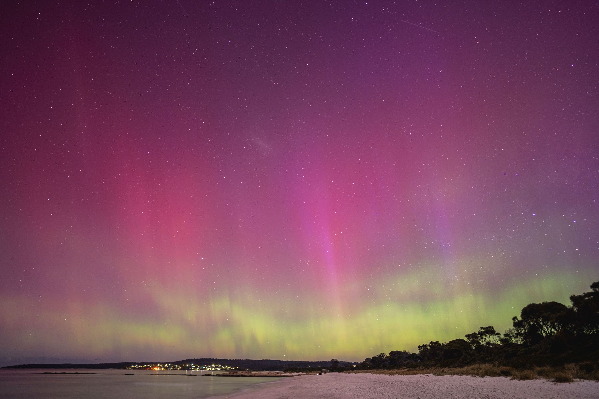 Aurora Australis glowing pink and green over the beach at Binalong Bay