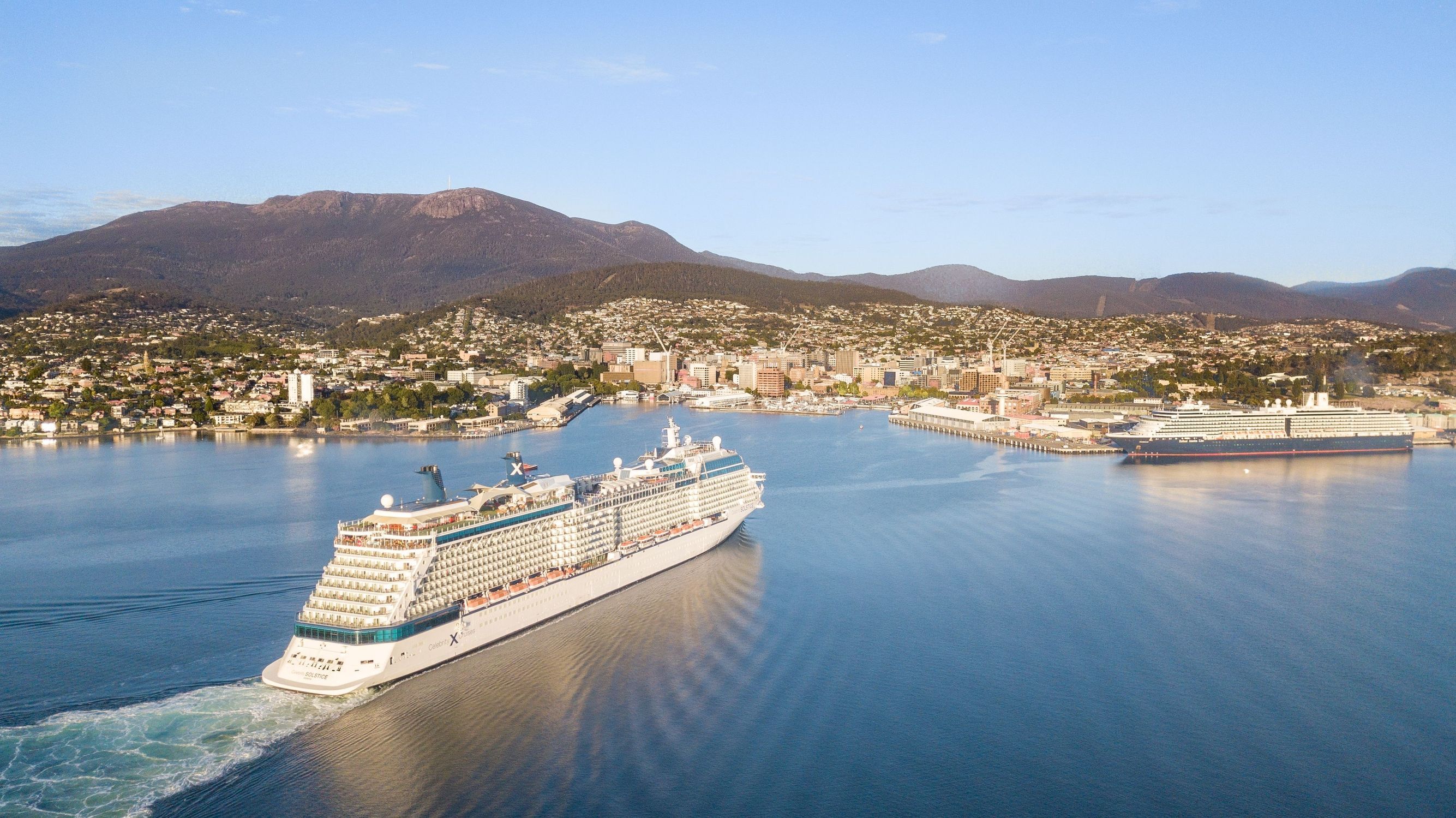 Celebrity Solstice and Noordam cruise ships on the water with kunanyi / Mount Wellington and Hobart behind