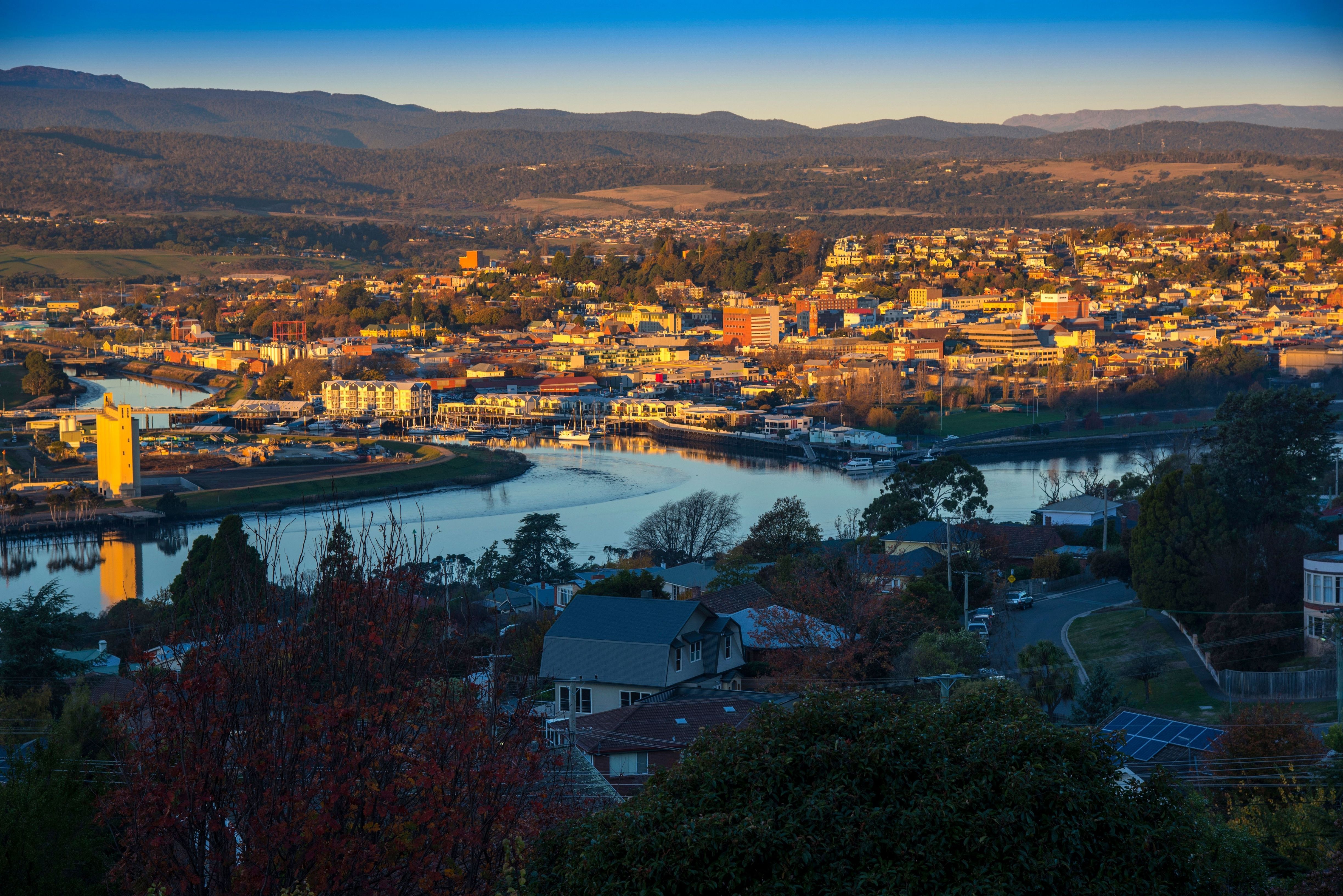 Elevated golden hour view of Launceston with Seaport Boulevard and kanamaluka / River Tamar winding below distant mountains