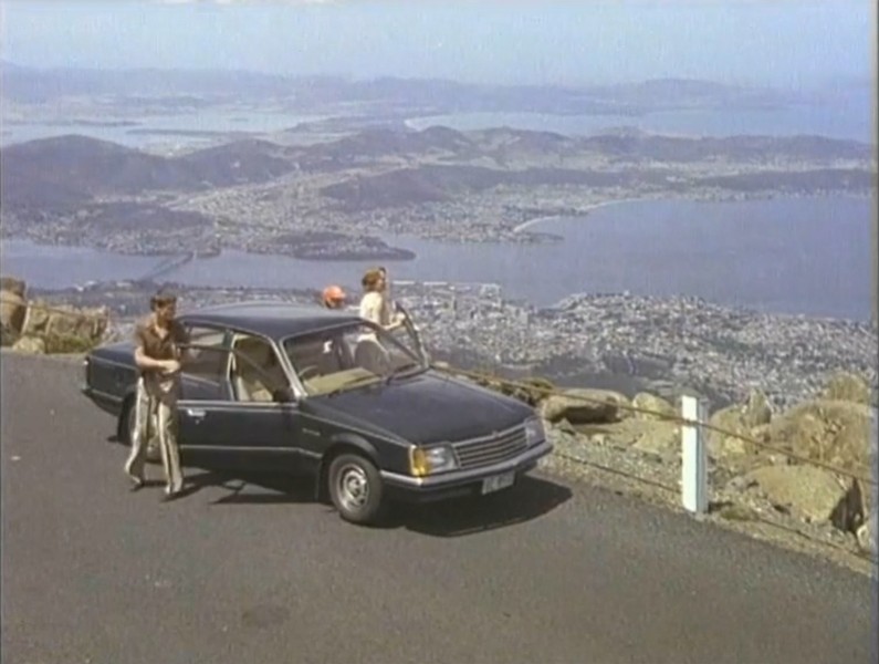 Video screengrab from the 1980 Freewheelin' around Tasmania campaign with travellers and a car overlooking Hobart from kunanyi / Mount Wellington