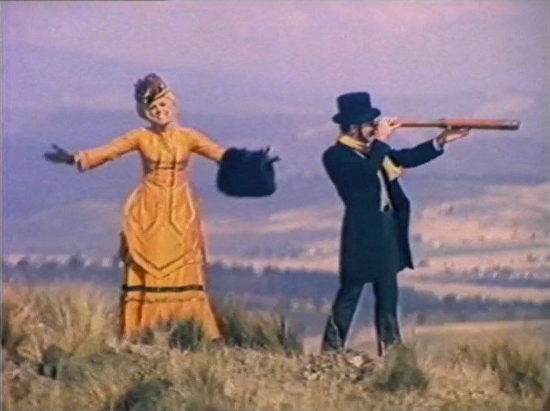 Video screengrab from the 1981 Great Winter Holiday Isle campaign featuring two people in Victorian era costume on a Tasmanian hillside