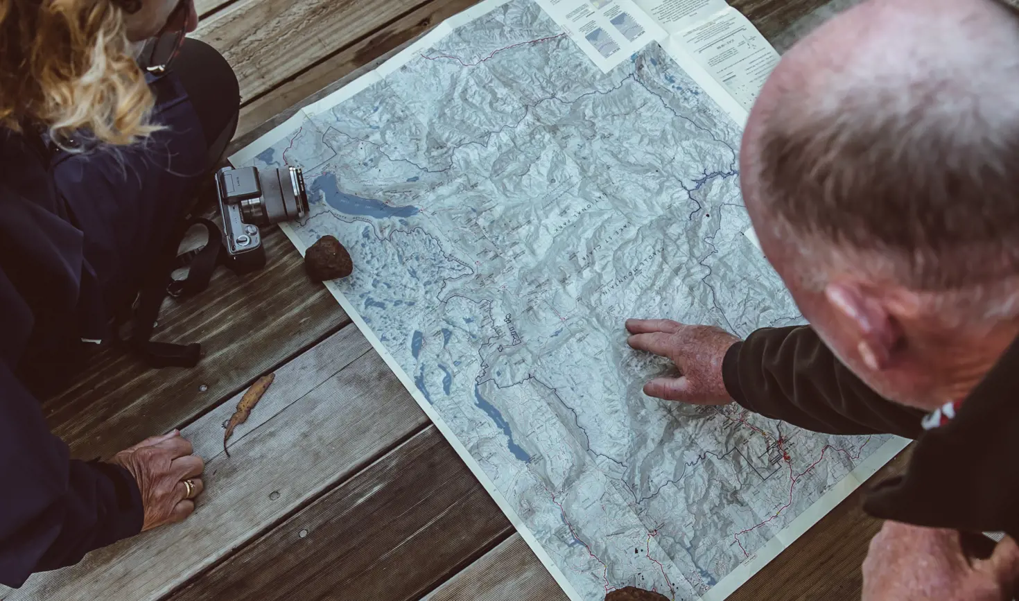 Overhead view of two people studying a map of Cradle Mountain-Lake St Clair National Park, planning their Overland Track walk