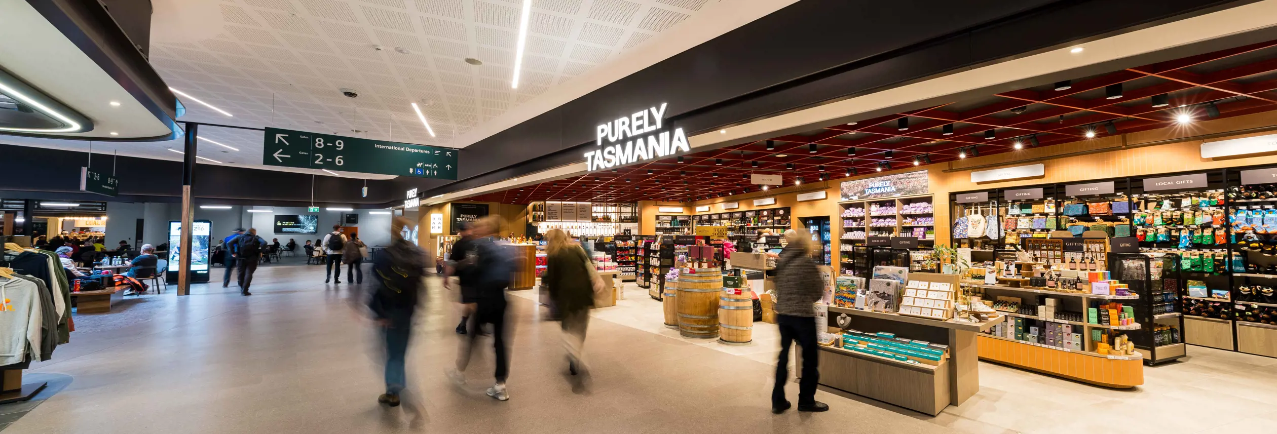 Travellers walk through Hobart International Airport terminal past the Purely Tasmania retail store stocked with local gifts