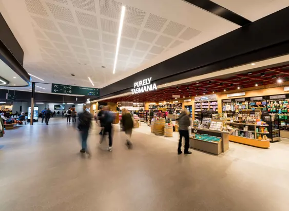 Travellers walk through Hobart International Airport terminal past the Purely Tasmania retail store stocked with local gifts