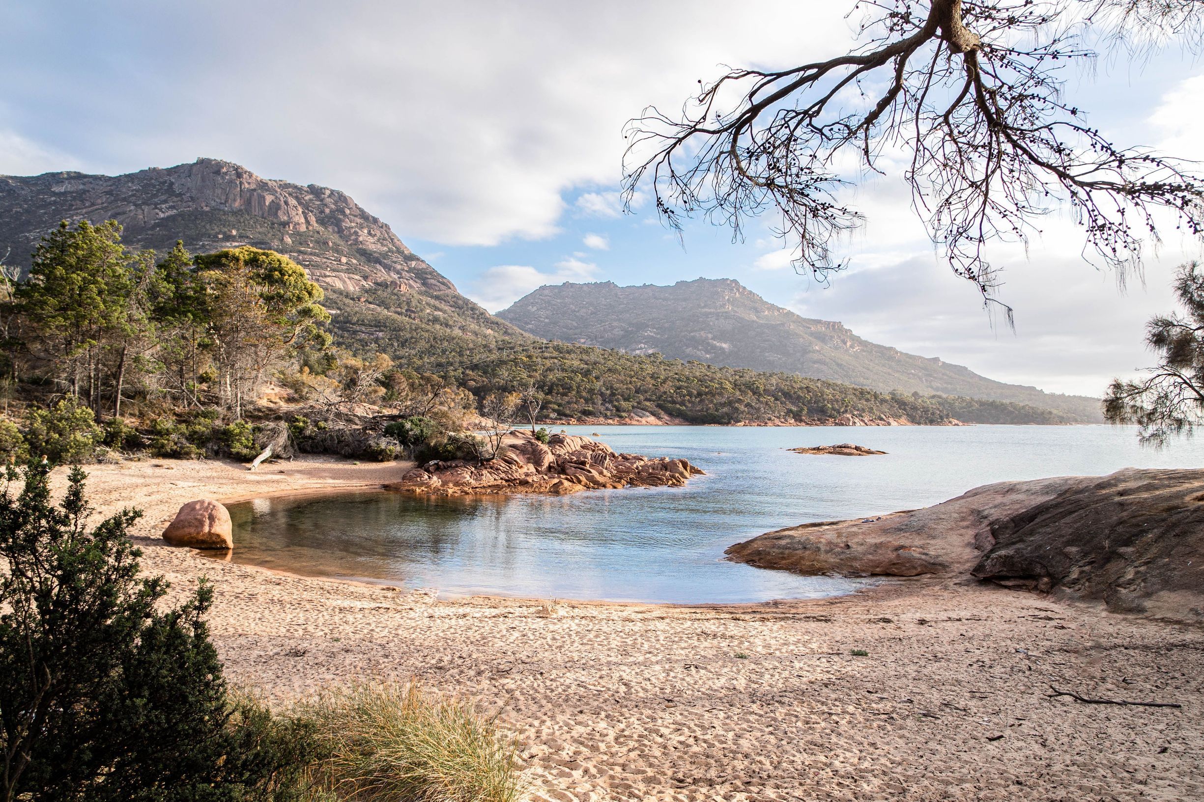 Honeymoon Bay with a sandy beach, granite boulders, calm water and The Hazards beyond, Freycinet National Park