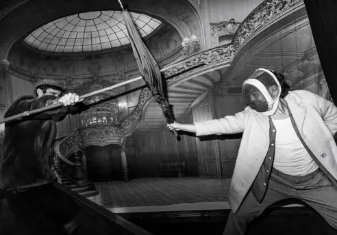 Black and white image of two people fencing with umbrellas in an ornate interior at The Secret Bank Society, Ringarooma