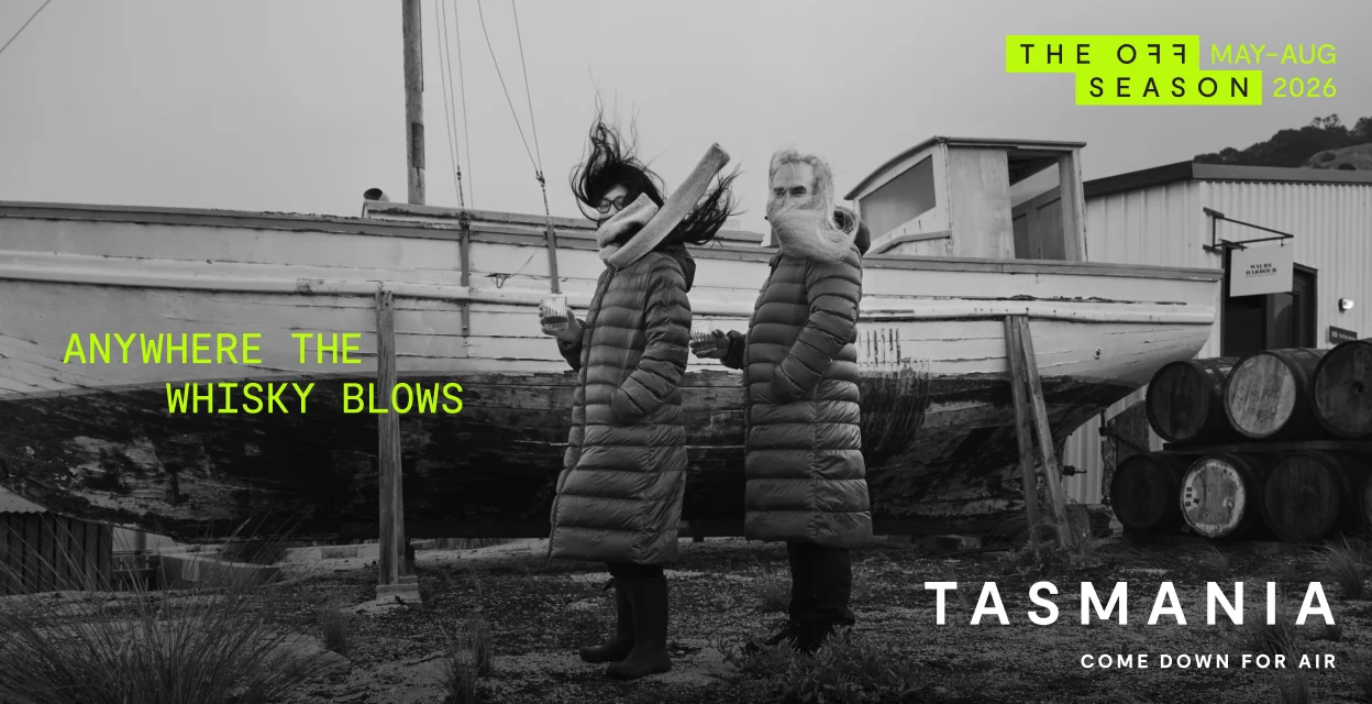 Off Season campaign ad titled Anywhere The Whisky Blows showing two people holding whisky in the wind beside a boat