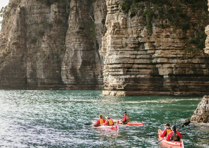 Sea kayakers paddle along dramatic coastal cliffs at Turrakana / Tasman National Park with Southern Sea VentureSea kayakers paddle along dramatic coastal cliffs at Turrakana / Tasman Peninsula with Southern Sea Ventures