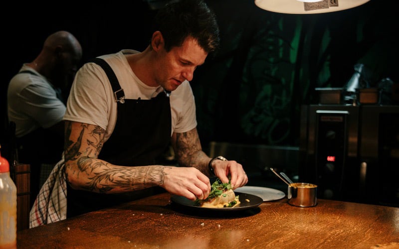 Ben Milbourne arranging micro-greens on a signature dish 