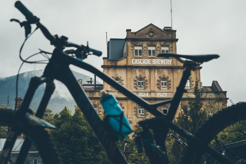 A mountain bike is parked in the foreground of a photograph of the 200 year old facade of the Cascade Brewery in South Hobart.