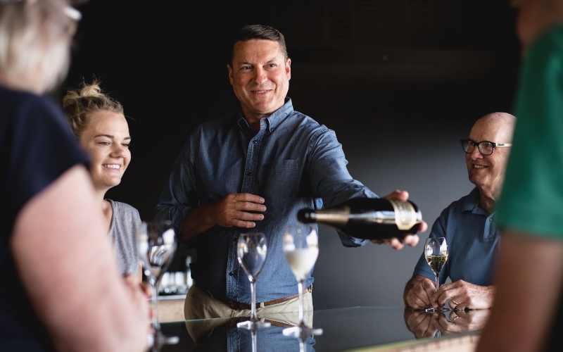 A sommelier talks with a small goup of wine enthusiasts over the bar in te tasting room at Clover Hill Wines.