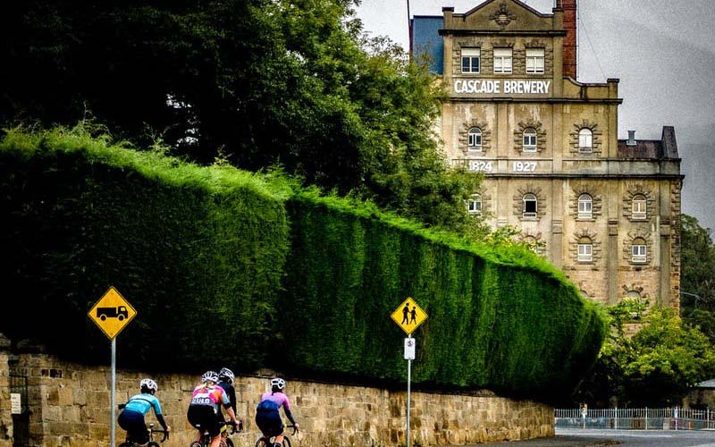 Cyclists ride on Cascade Road, Hobart, passing the iconic Cascade Brewery. 
