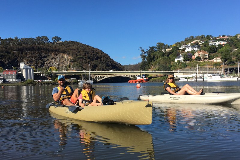 A young family float in two kayaks on the calm waters of the kanamalukaTamar River 