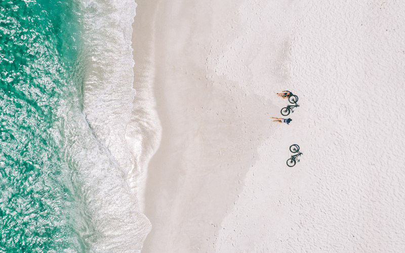 Birds eye view of two cyclists resting on an east coast beach, Tasmania