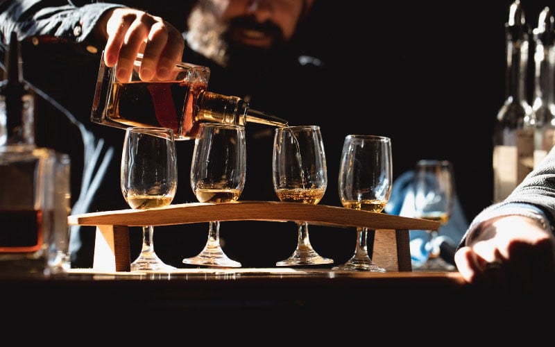 A man is pouring a flight of Tasmanian Whisky 