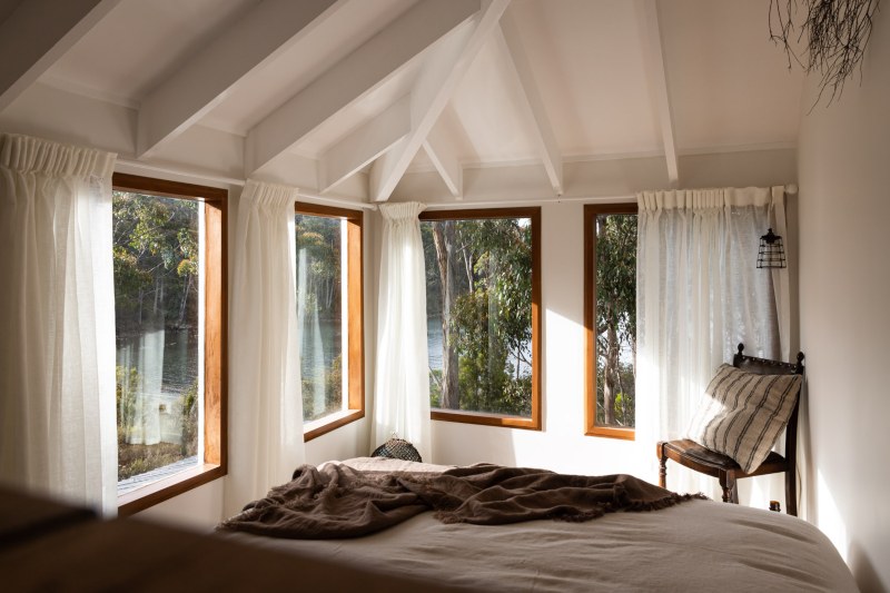 The bedroom of The Voyager features large windows looking out orm a white, tastefully decorated interior.