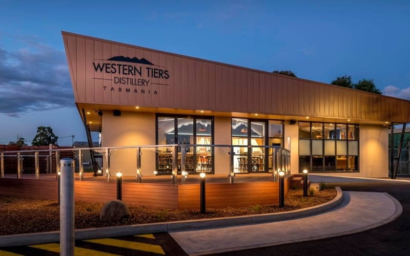 The angular roof the Western Tiers Dstillery is lit by warm lights in the early evening.